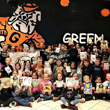Students proudly displaying their books at Green Schools